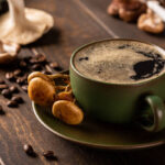 Coffee with mushrooms in green cup on wooden background. New Superfood trendy healthy concept with copy space, selective focus.